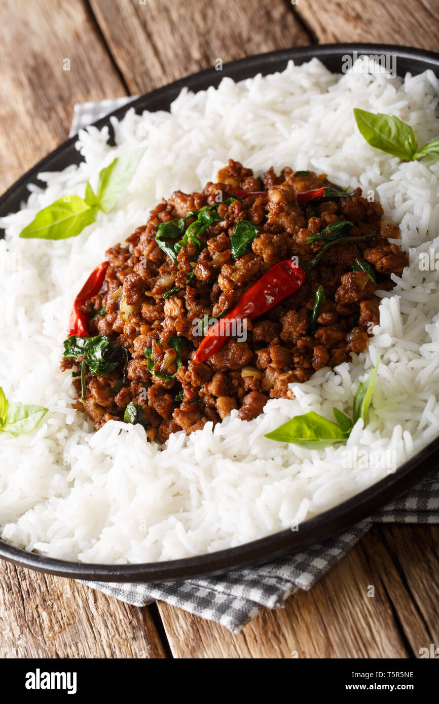 Basilico tailandese di pollo (Gai Pad Krapow) con riso close-up su una piastra sul piano verticale. Foto Stock