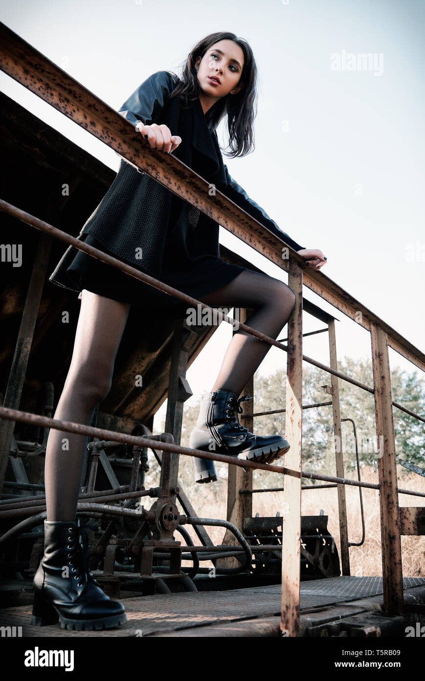 Moda shot: ritratto della bella ragazza rock (modello informale) vestita di nero giacca e gonna permanente sulla carrozza del treno Foto Stock