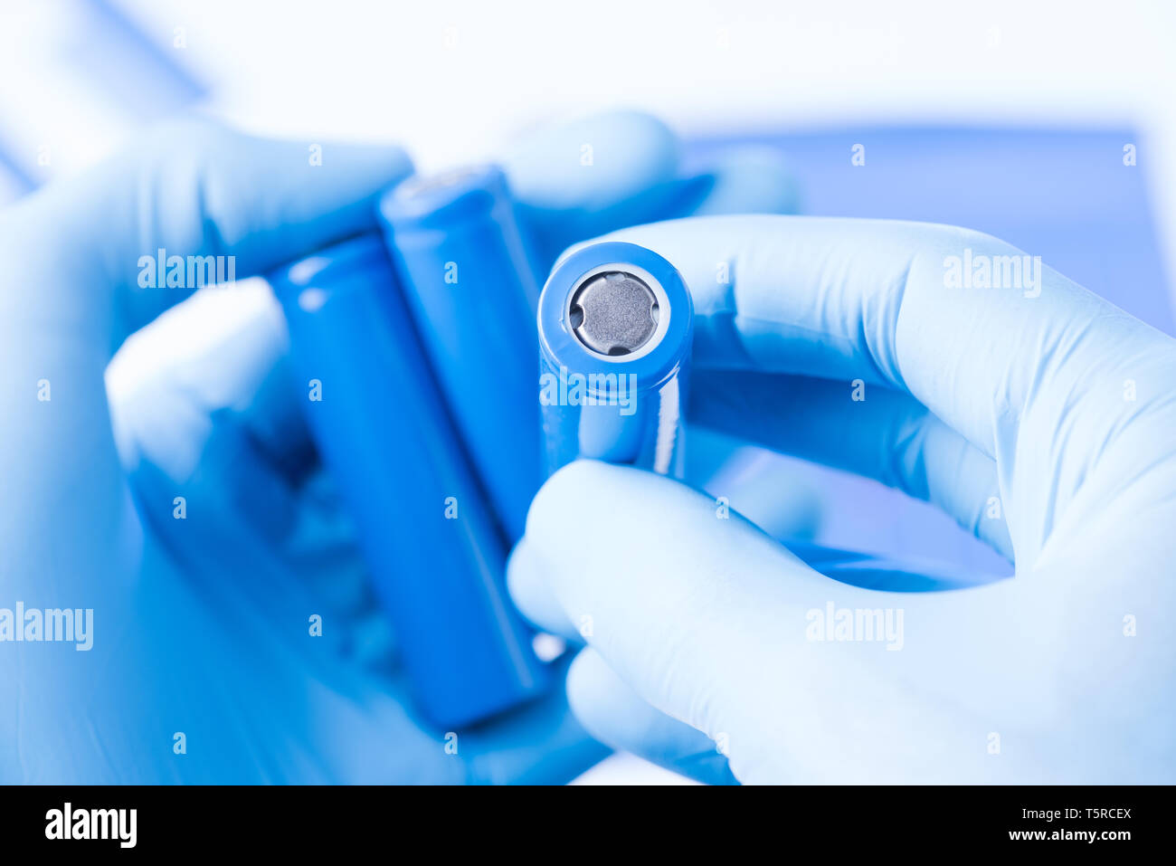 Scienziato tenere in mano in guanti di protezione piccola batteria di accumulatori, nuovo tipo di batteria ricaricabile il concetto di ricerca Foto Stock