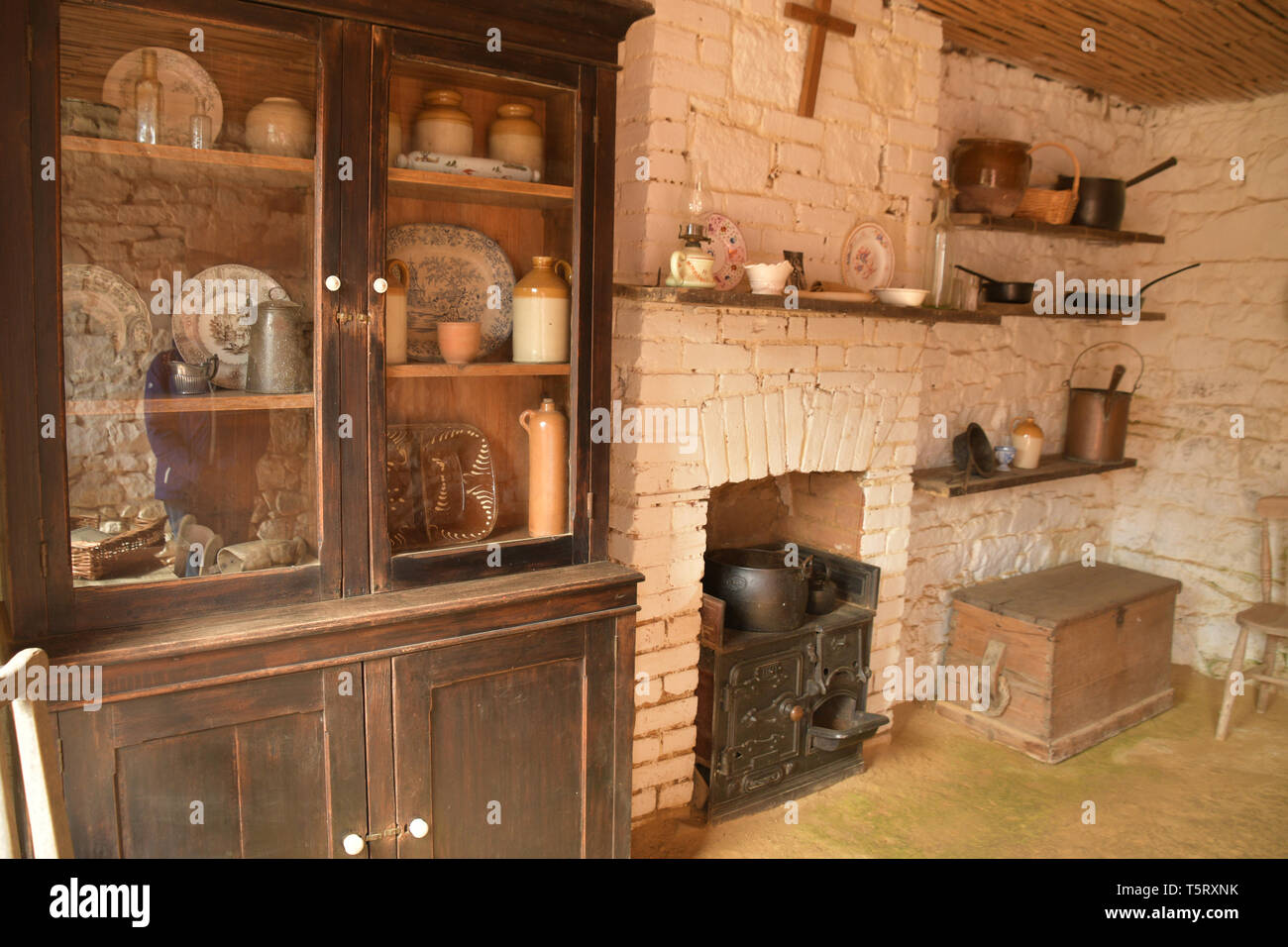 Tipica piccola cucina con ghisa cucina, cabinet per conservazione e varie pentole padelle e contenitori di terracotta di una casa colonica del XVIII secolo a th Foto Stock
