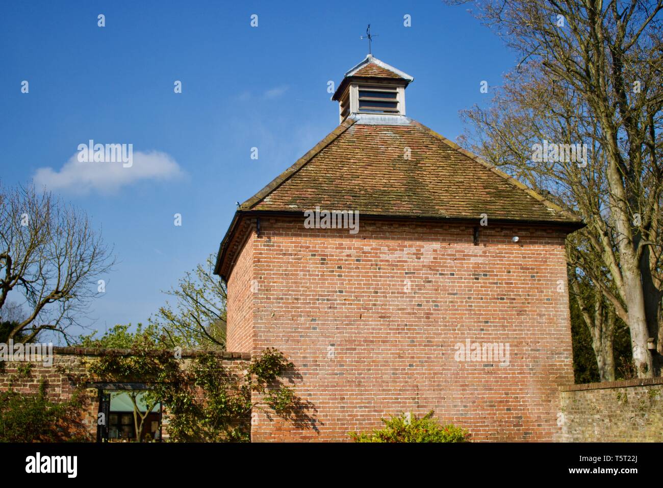 Vecchia costruita in mattoni colomba cote con terracotta tetto di tegole contro il cielo blu - immagine Foto Stock