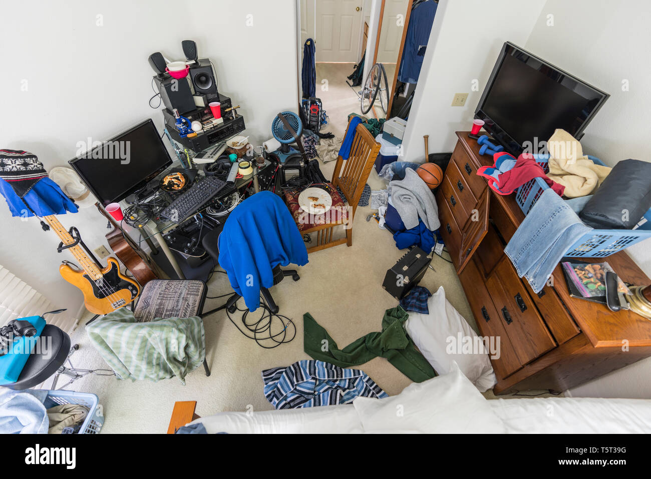 Molto disordinato e caotico Suburban Teenage boys camera da letto con pile di vestiti, musica e attrezzature sportive. Foto Stock