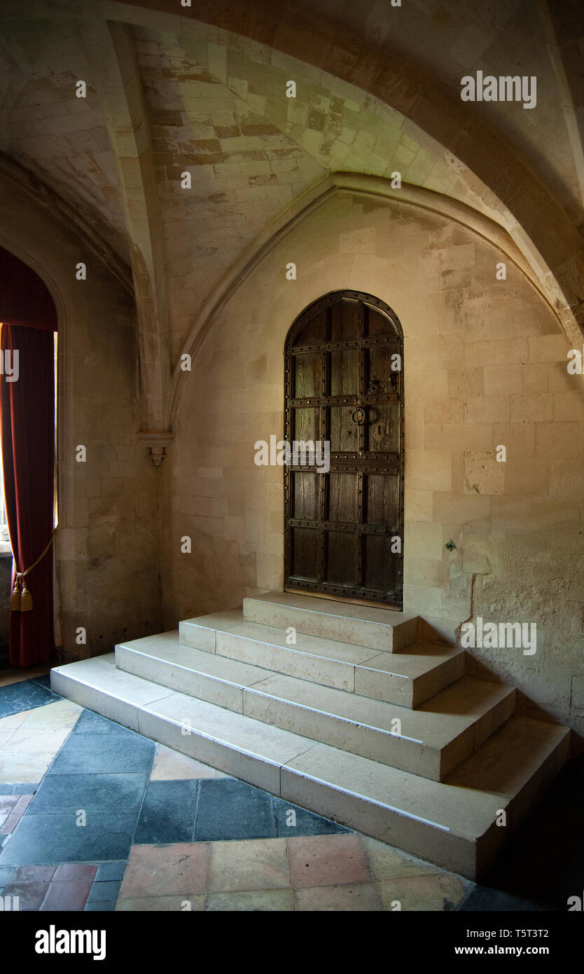 Gradini in pietra e una porta di legno nel medioevo sala da pranzo a Anglesey Abbey, lode, Cambridgeshire. Essa era parte dell'originale convento agostiniano. Foto Stock