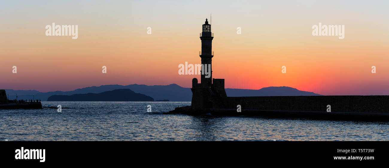 La silhoutte del faro nel porto di Chania, una città sull'isola di Creta, Grecia durante il tramonto. Foto Stock