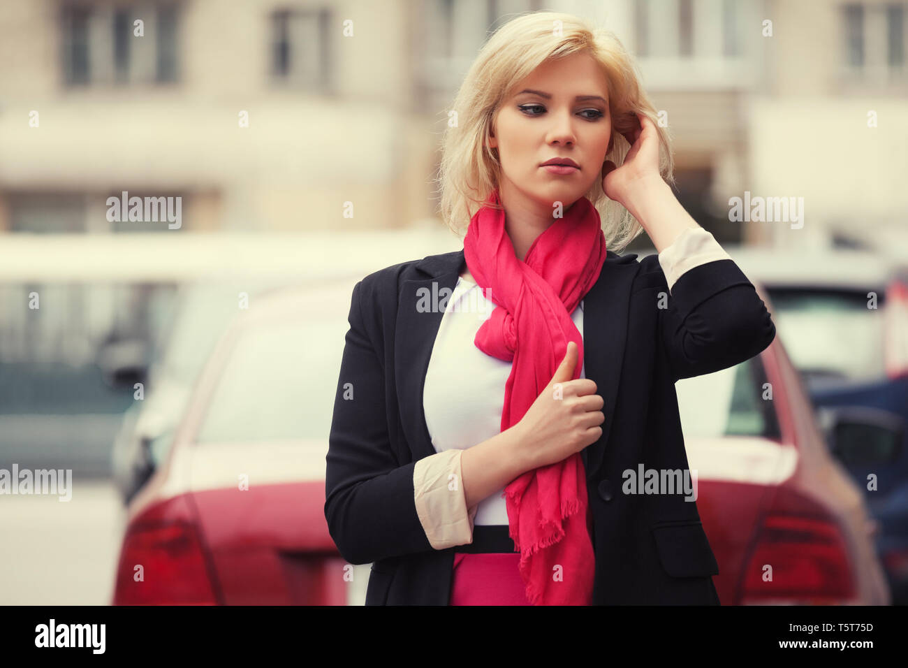 Moda giovane donna di affari a piedi nella città strada elegante modello femminile indossando abito nero giacca e sciarpa rossa all'aperto Foto Stock