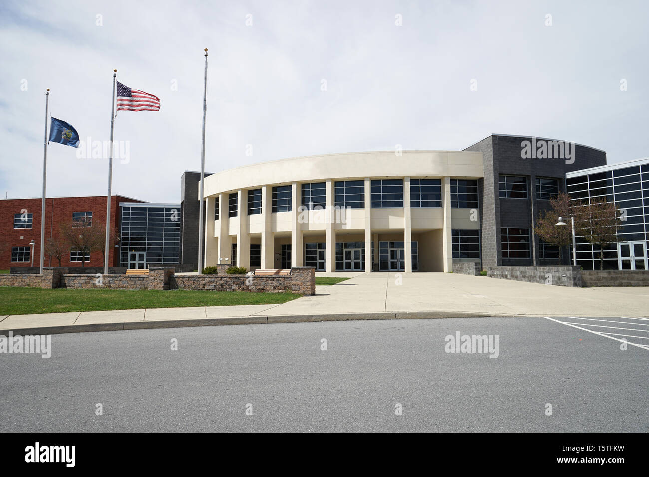 Esterno di un moderno edificio scolastico con copyspace. Vi è una bandiera americana e una Pennsylvania bandiera di stato sui pennoni. Foto Stock