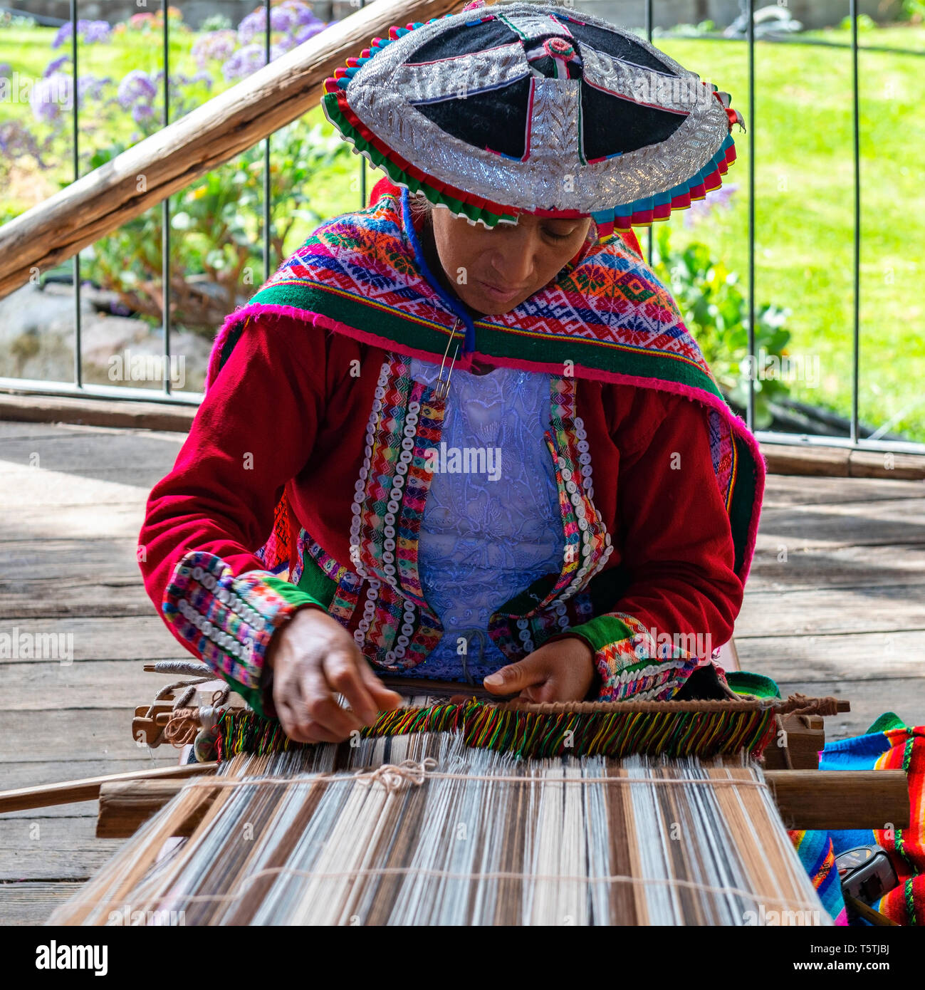 Un Quechua donna indigena che mostra la tecnica di tessitura e la produzione di tessili nella Cordigliera delle Ande del sud America in Cusco, Perù. Foto Stock
