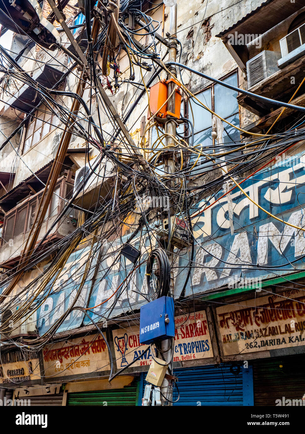 Caotico groviglio di fili per illuminazione stradale le forniture di elettricità e i cavi telefonici in una strada della città vecchia di Delhi India del Nord Foto Stock