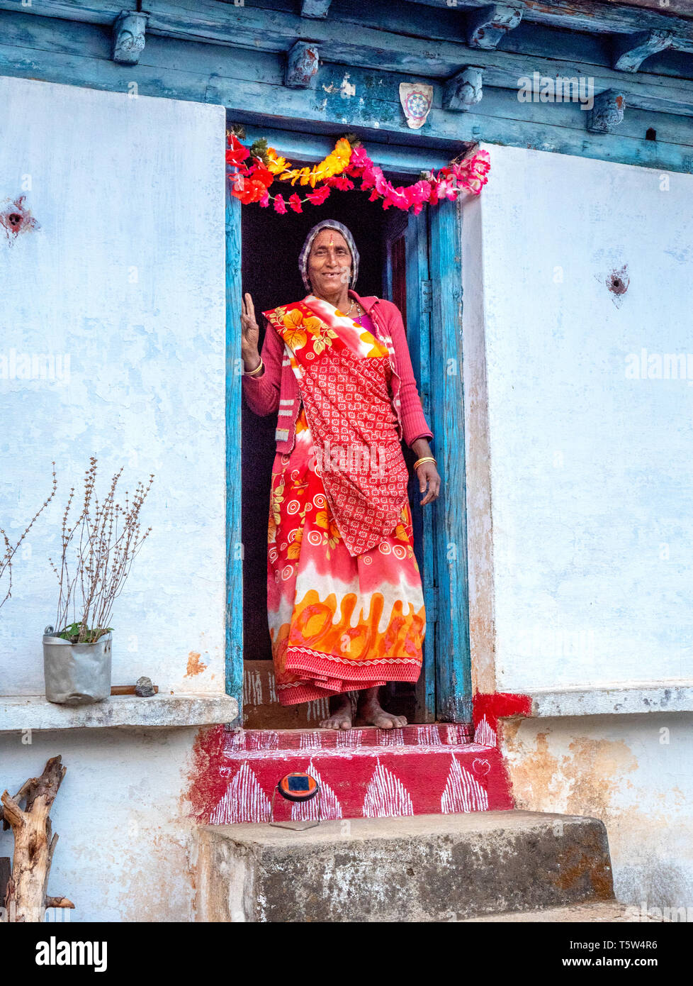 Donna sul decorate e blasonata soglia di casa in remoto villaggio di Satri nella regione di Binsar di Uttarakhand Himalaya Foto Stock