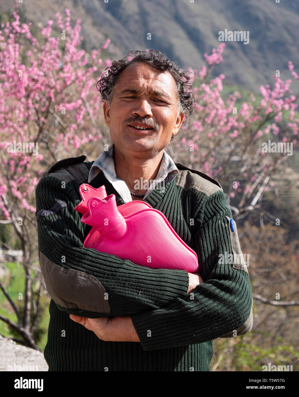 Sorridenti guest house keeper in un piccolo villaggio di montagna nella valle Saryu in Uttarakhand India del Nord rosa porta bottiglie di acqua calda. Foto Stock