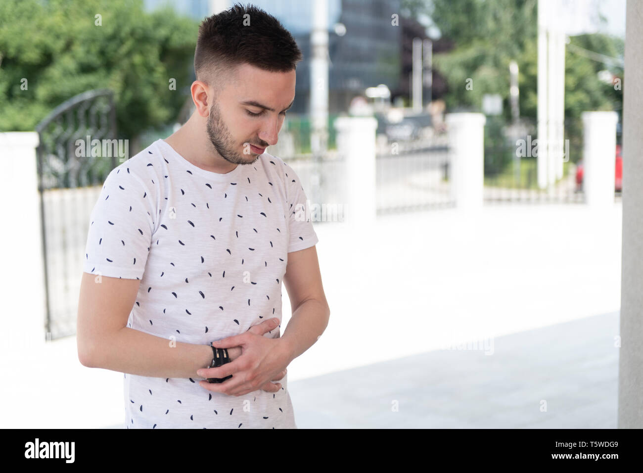 Attraente uomo rendendo tradizionale preghiera a Dio Allah all'aperto davanti alla moschea Foto Stock