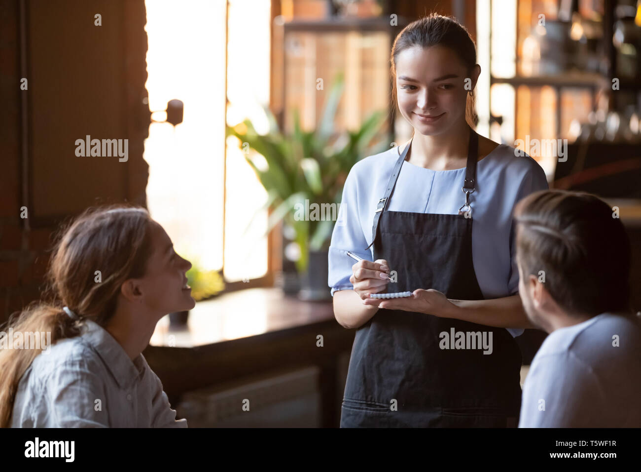 Sorridente cameriera serve una coppia sposata prendere fine Foto Stock