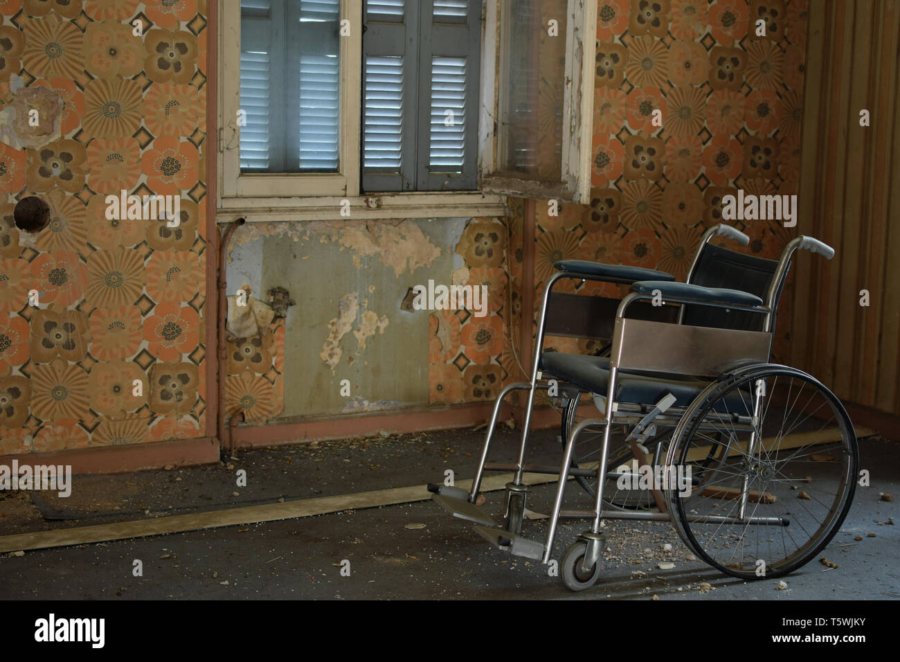 Vintage peeling per sedie a rotelle a parete e pavimento polveroso nella vecchia casa abbandonata. Foto Stock