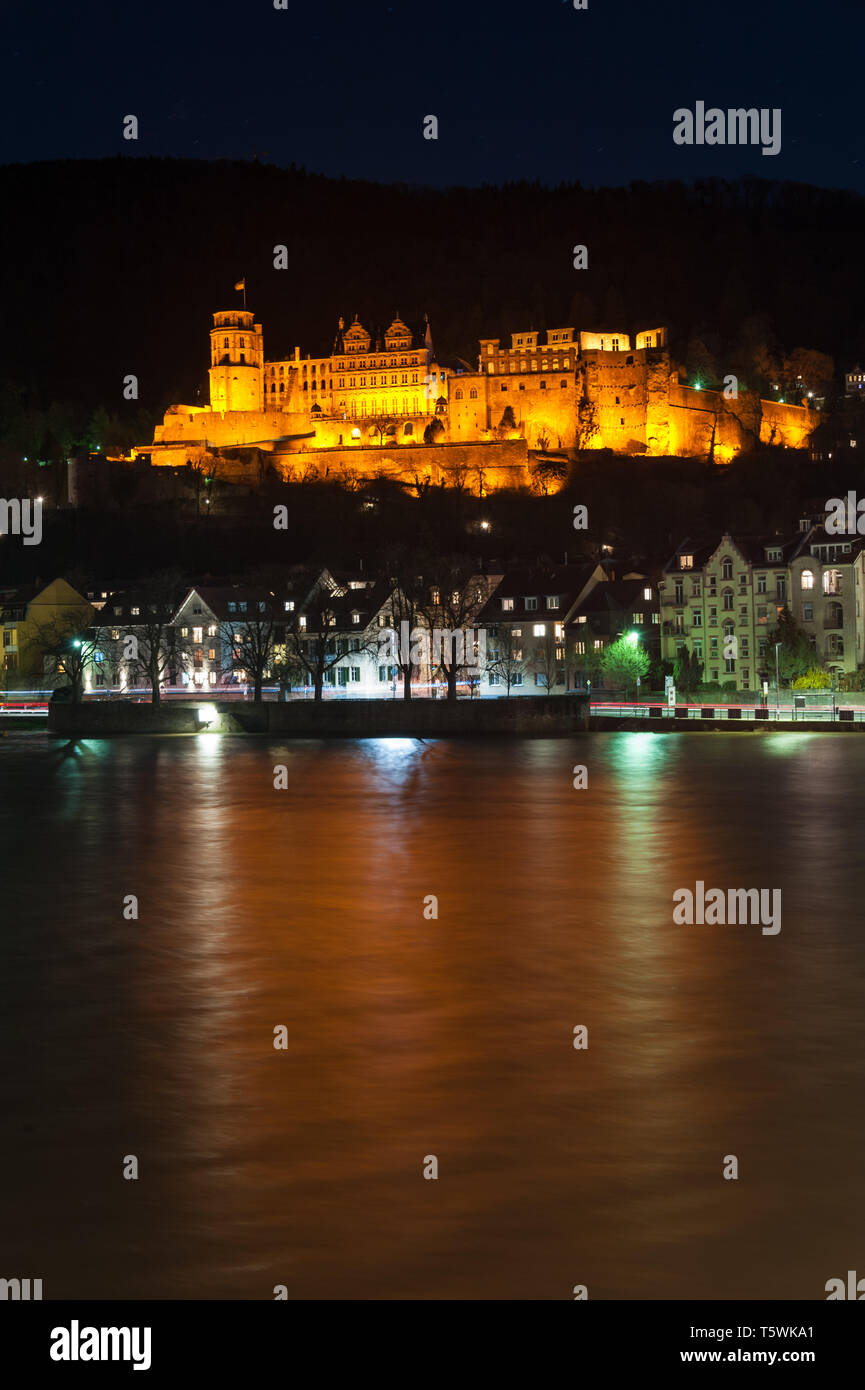 Heidelbergs castello illuminato catturato dal vecchio ponte della città con i riflessi di luce sull'acqua del fiume Neckar Foto Stock