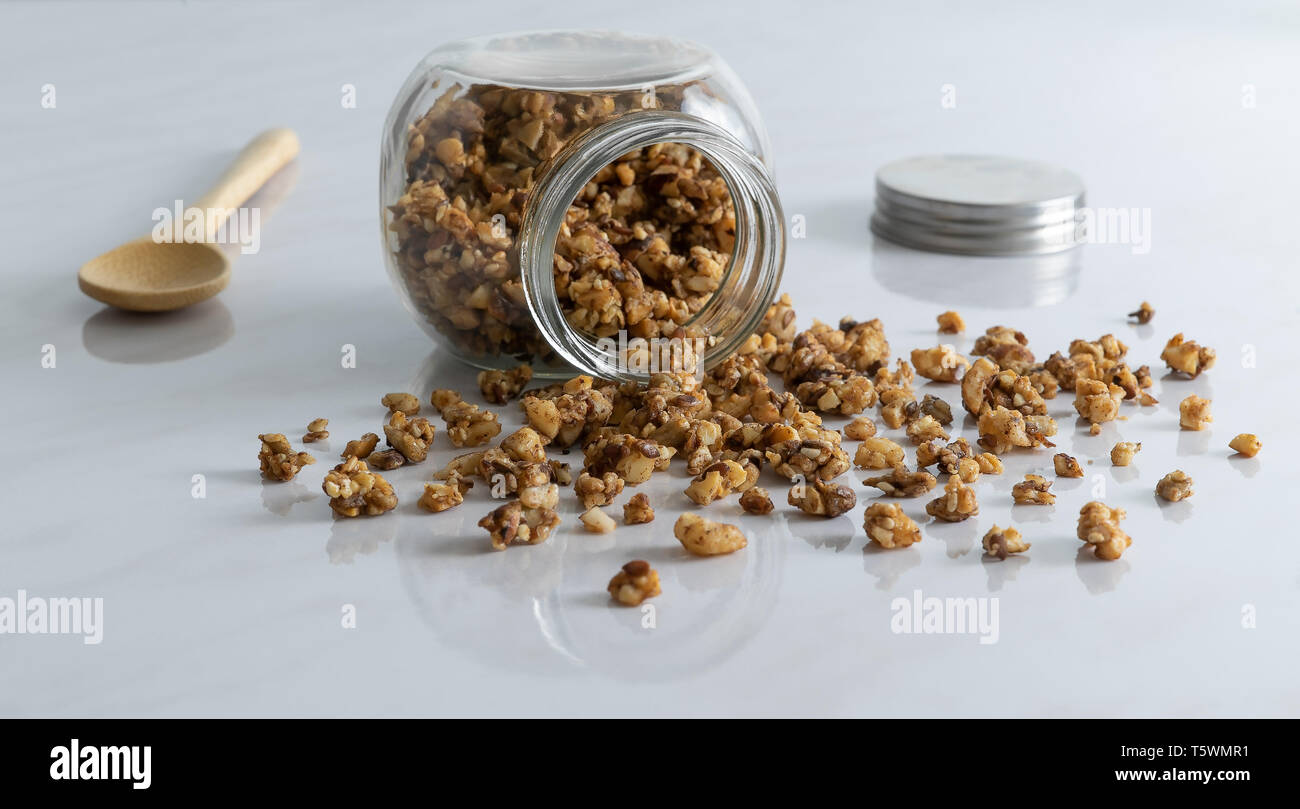 In casa sano e nutriente colazione granola in un vasetto di vetro con il cucchiaio di legno su pulire il marmo bianco tavolo da cucina in fresco. La luce del mattino. Foto Stock