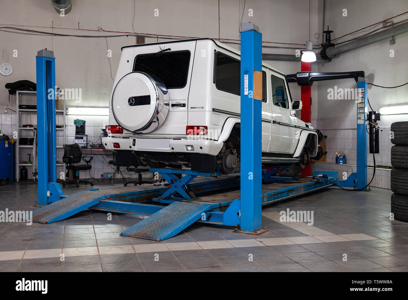 Novosibirsk, Russia - 08.01.2018: Bianco auto usate Mercedes G-classe senza ruote si erge sul supporto ruota di convergenza di allineamento della vettura nel wor Foto Stock