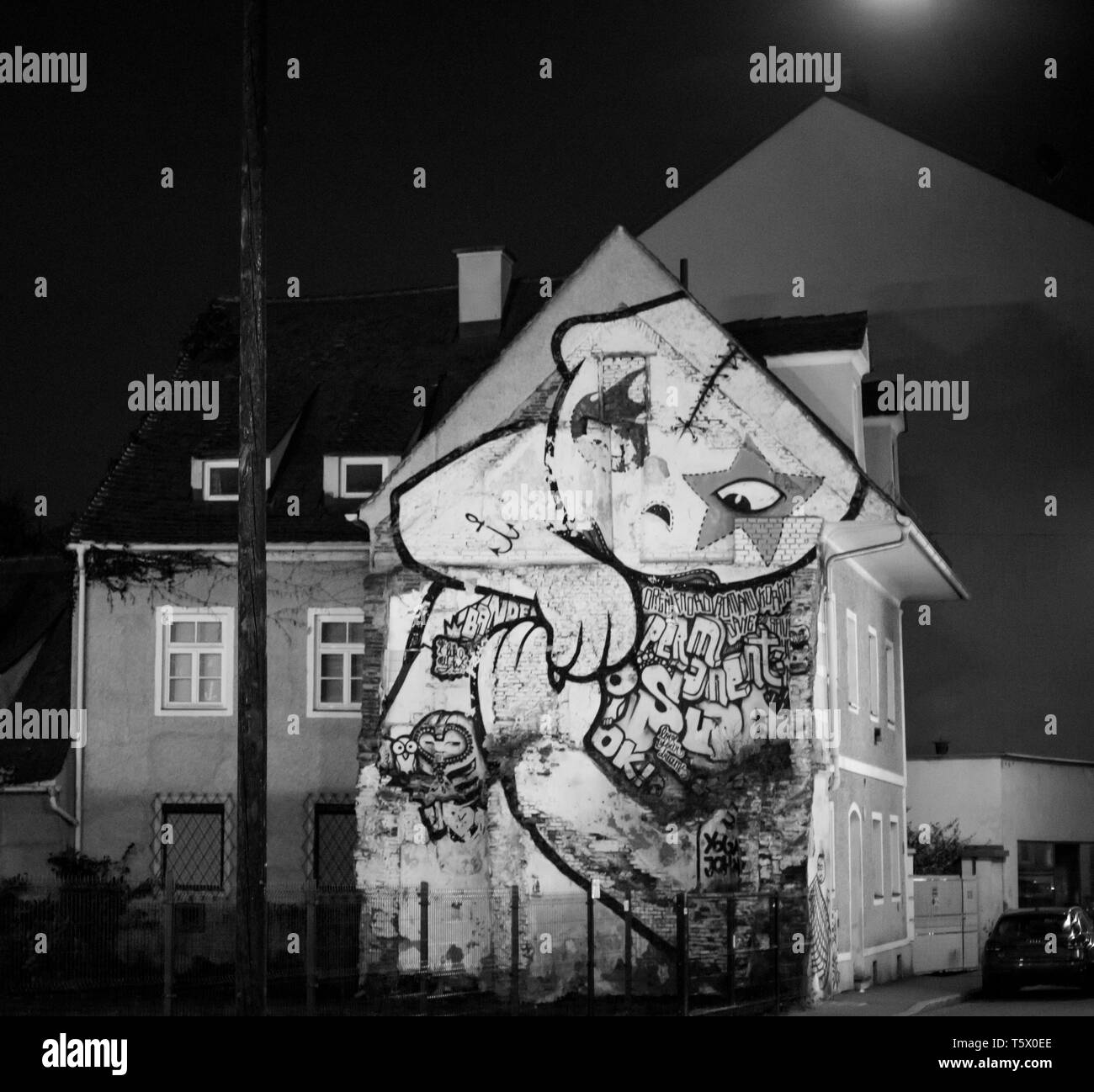Vista frontale di una casa urbana con una massiccia graffiti sulla facciata in una grande città di notte Foto Stock