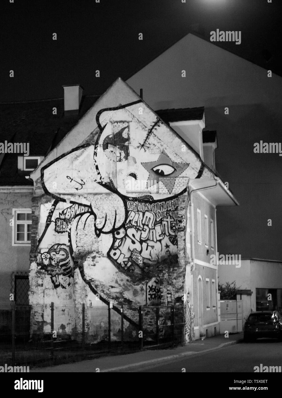 Vista frontale di una casa urbana con una massiccia graffiti sulla facciata in una grande città di notte Foto Stock