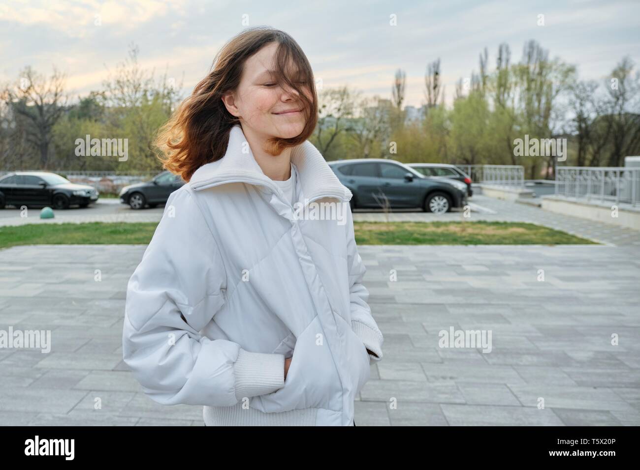 Outdoor ritratto della ragazza adolescente di quindici anni, ragazza sorridente con capelli lunghi marrone in camicia bianca. Foto Stock