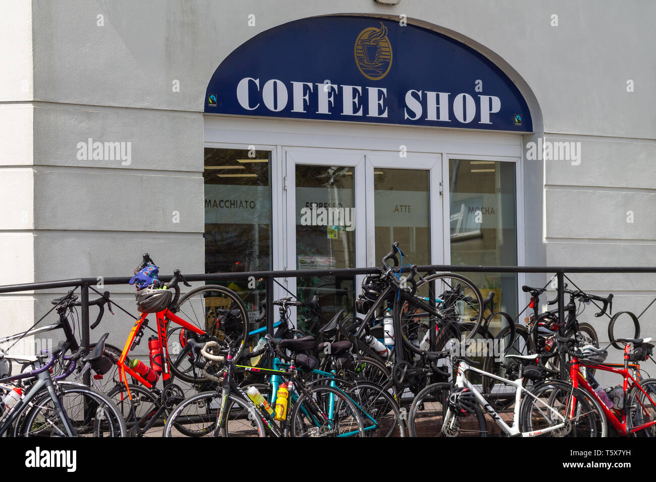 Biciclette impilate contro una ringhiera al di fuori di un coffee shop. Foto Stock