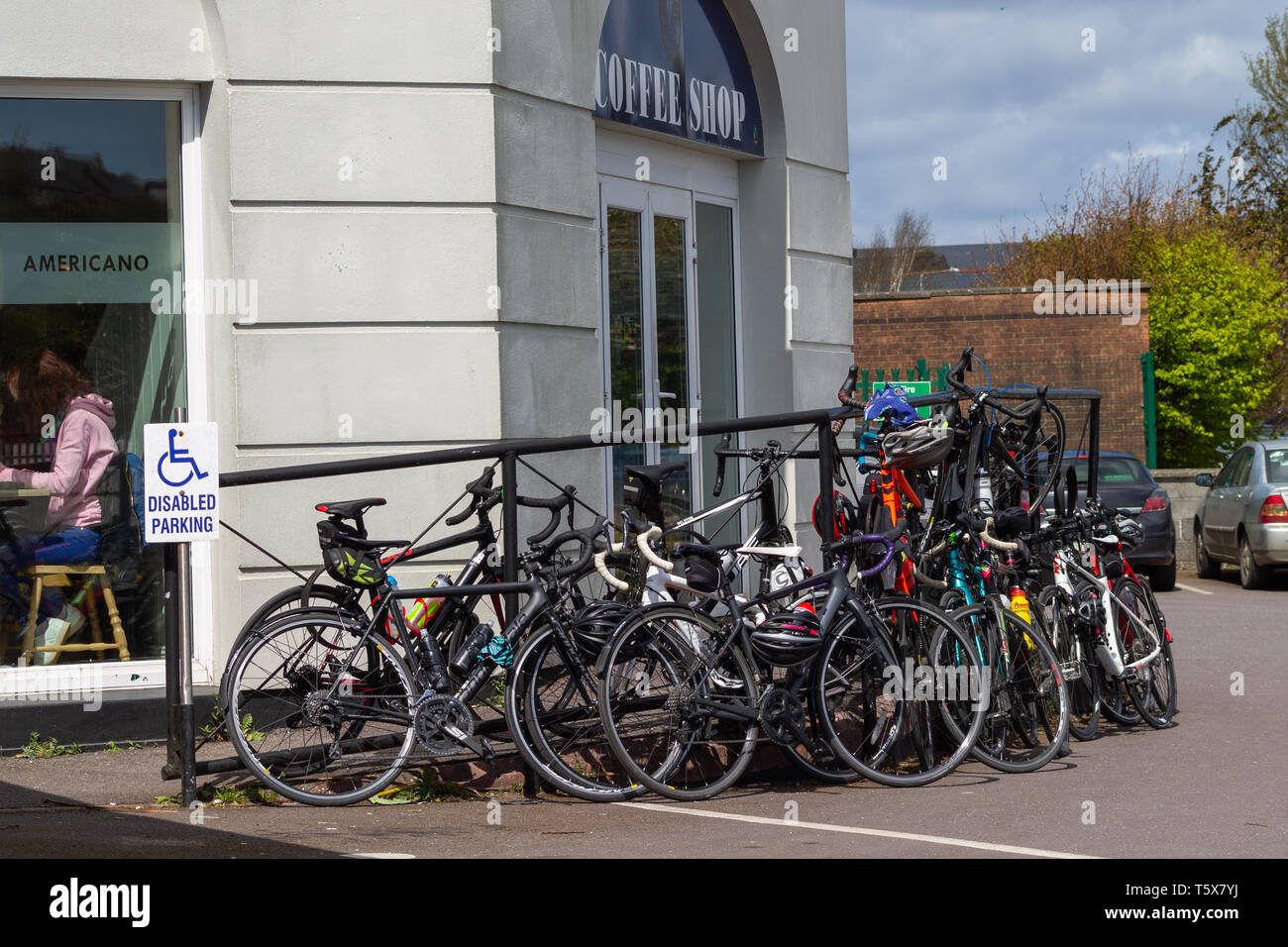 Biciclette impilate contro una ringhiera al di fuori di un coffee shop. Foto Stock
