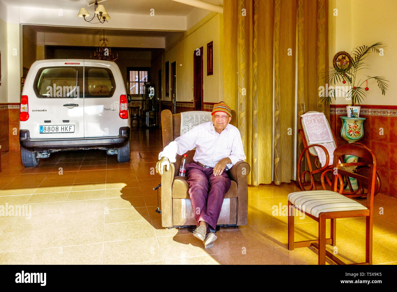 Anziano spagnolo seduto in un garage che assomiglia a un soggiorno nella regione di Valencia Senior Spain Europe pensionato da solo vecchio Spagna anziano popolazione Foto Stock