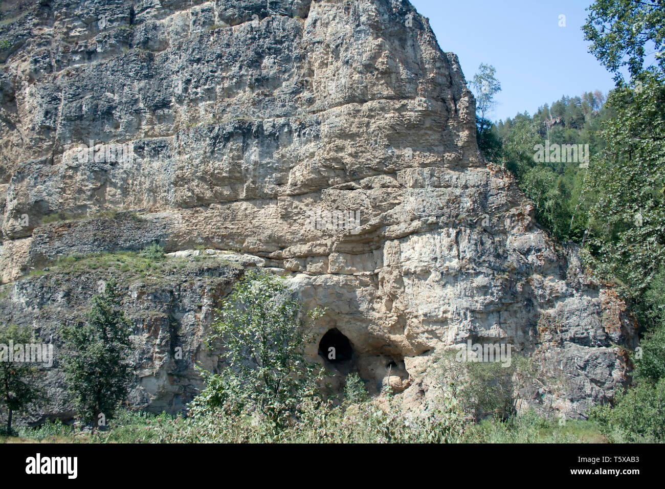 Grotta in montagna. Viaggiare a catena degli Urali. Cielo blu e verde della foresta Foto Stock