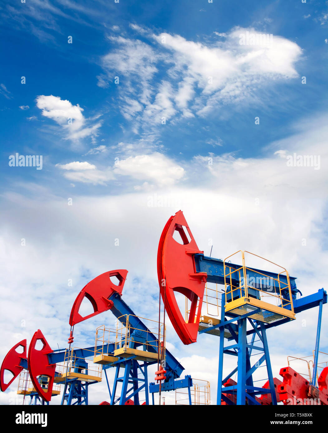 Gas e petrolio. Il lavoro della pompa olio jack su un campo petrolifero. Cielo blu e nuvole whitee. Foto Stock