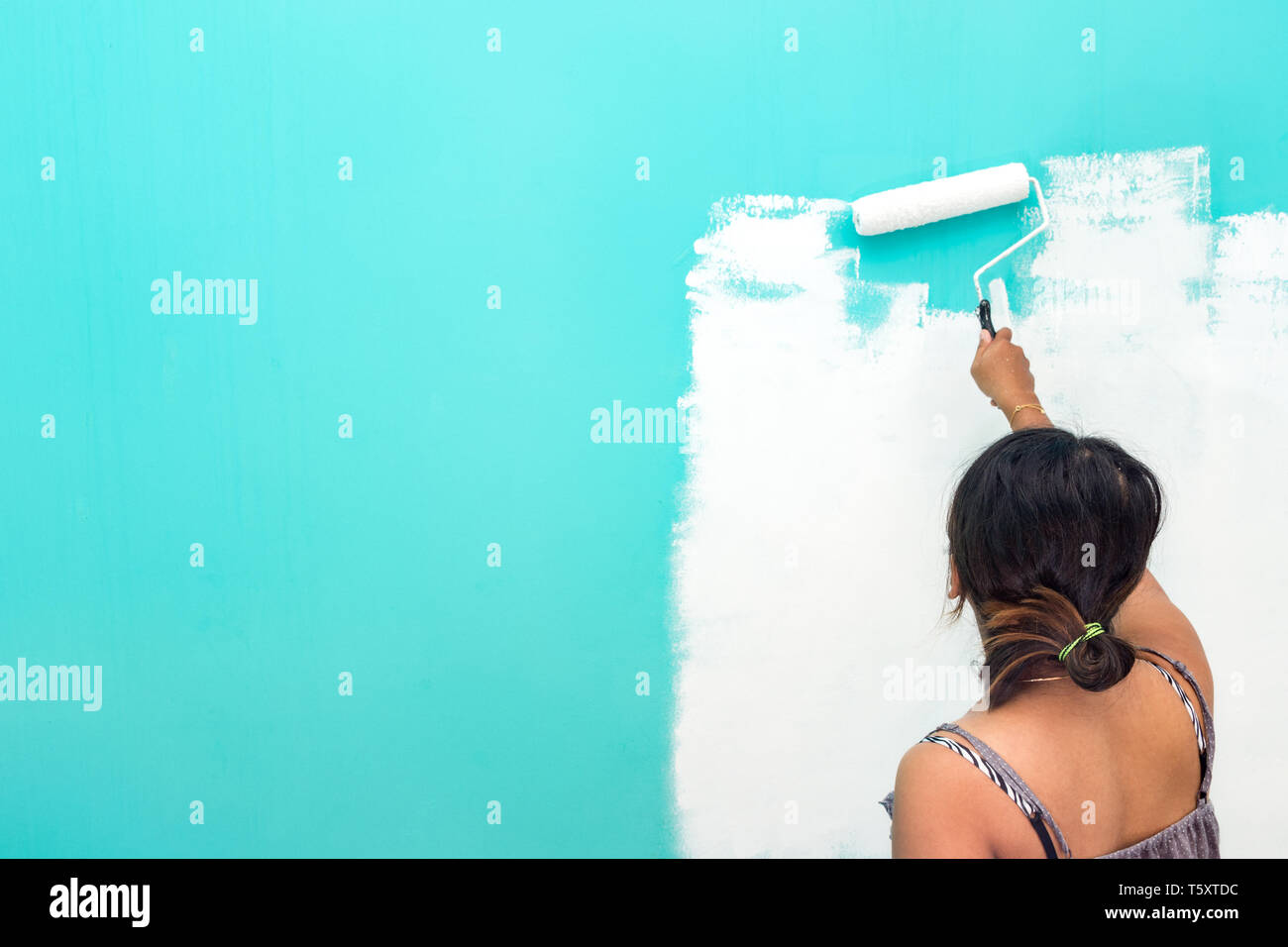Giovani asiatici non identificabili donna parete di verniciatura con vernice rullo e copiare lo spazio per testo Foto Stock