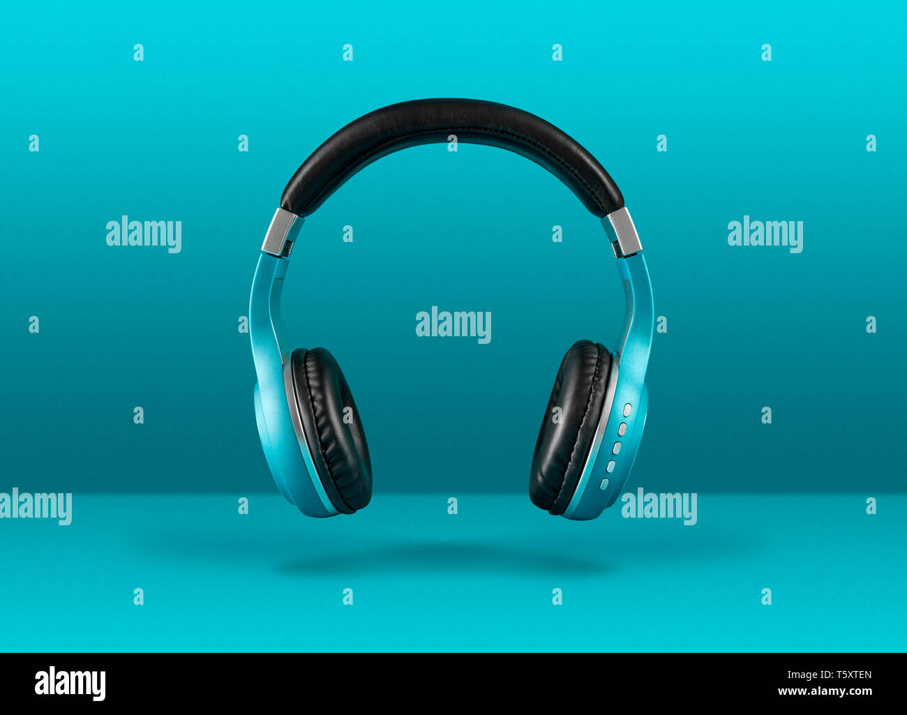 Moderne cuffie senza fili flottanti su sfondo blu con copyspace per il testo. Foto Stock