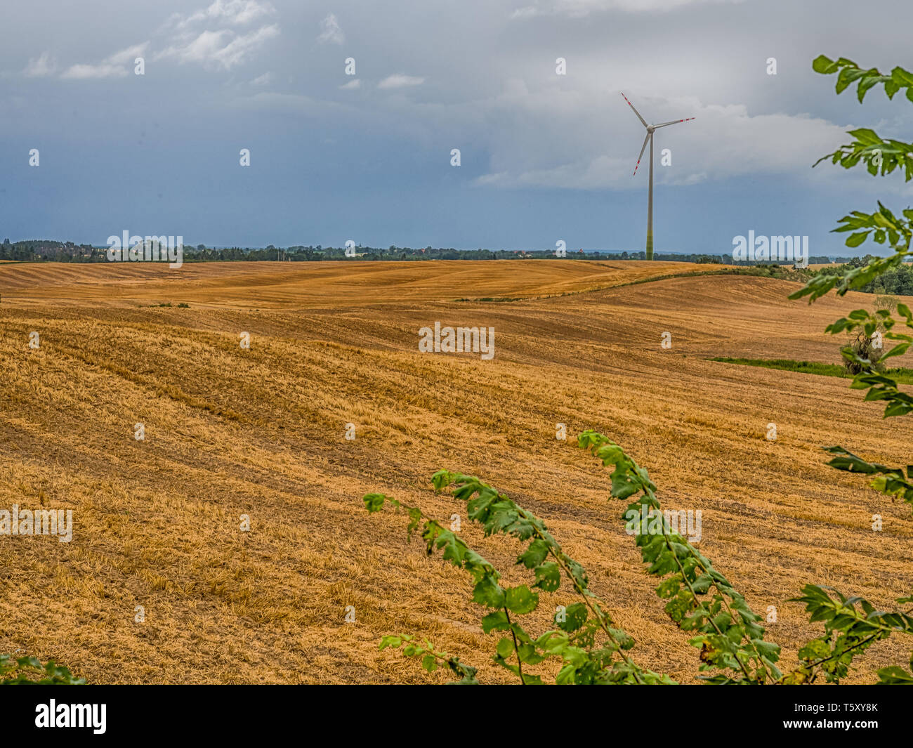 Un campo arato sulle colline con un vento da convertitore di energia. Esso è un dispositivo che converte l'energia cinetica del vento in energia elettrica. La Polonia. Oriente Foto Stock