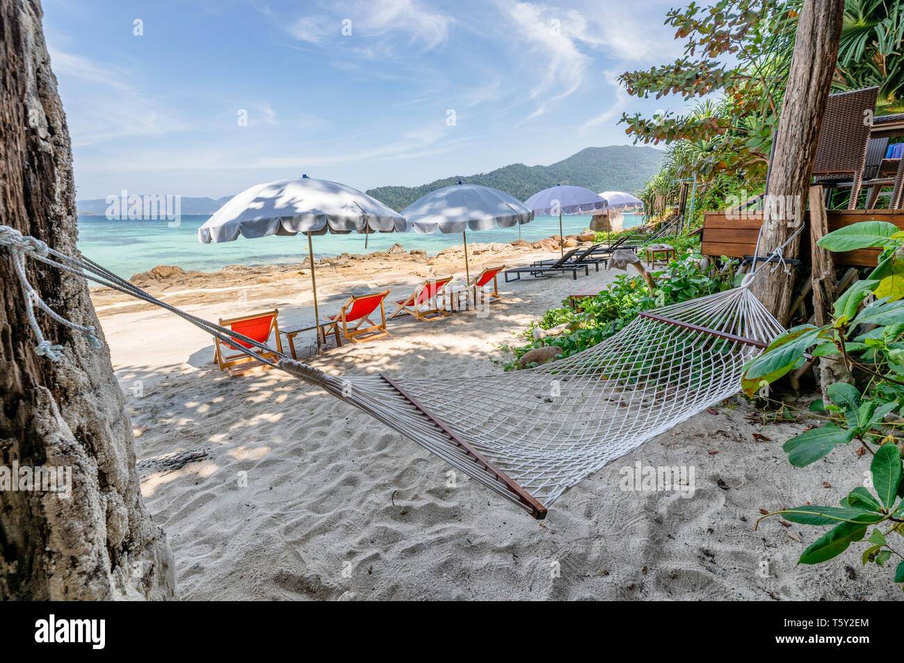 I lettini con ombrellone e swing corda sulla spiaggia in mare tropicale Foto Stock
