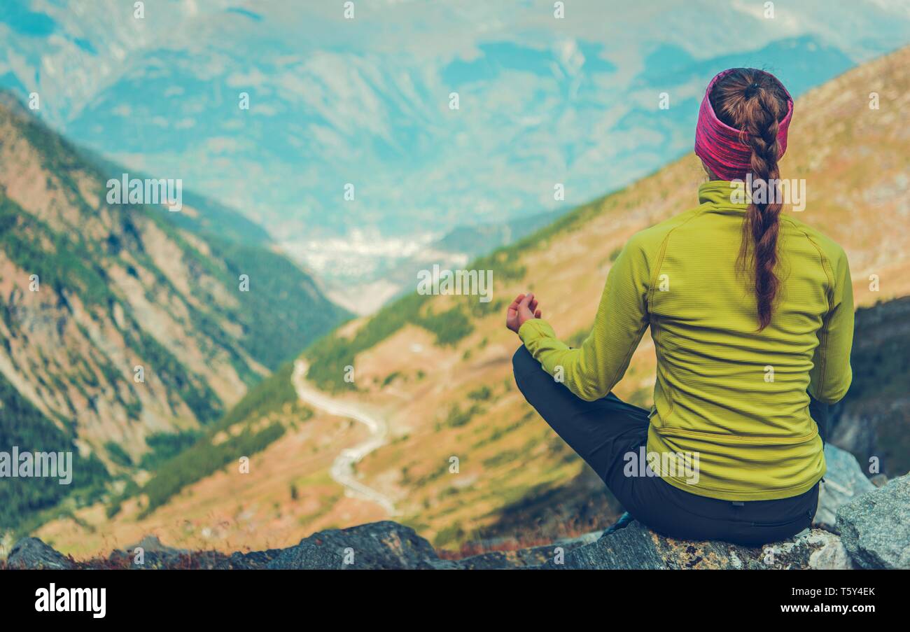 Giovane donna nel suo 30s meditazione Yoga sul Vertice di alpini. Foto Stock