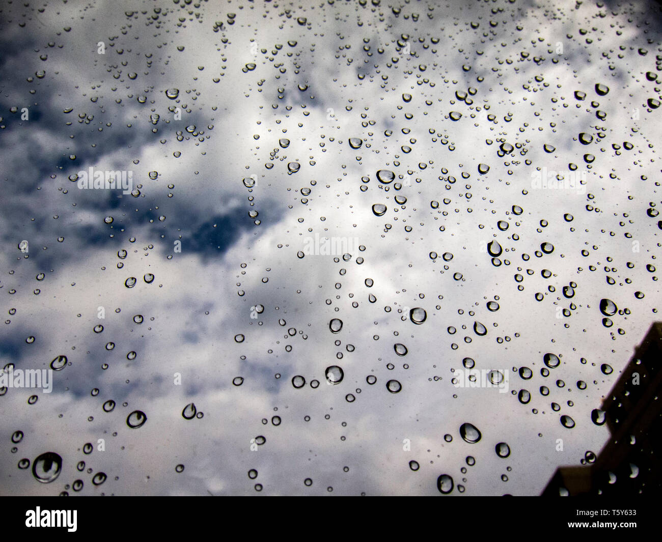 Droppletdrops di acqua sul vetro che riflette le nuvole Foto Stock
