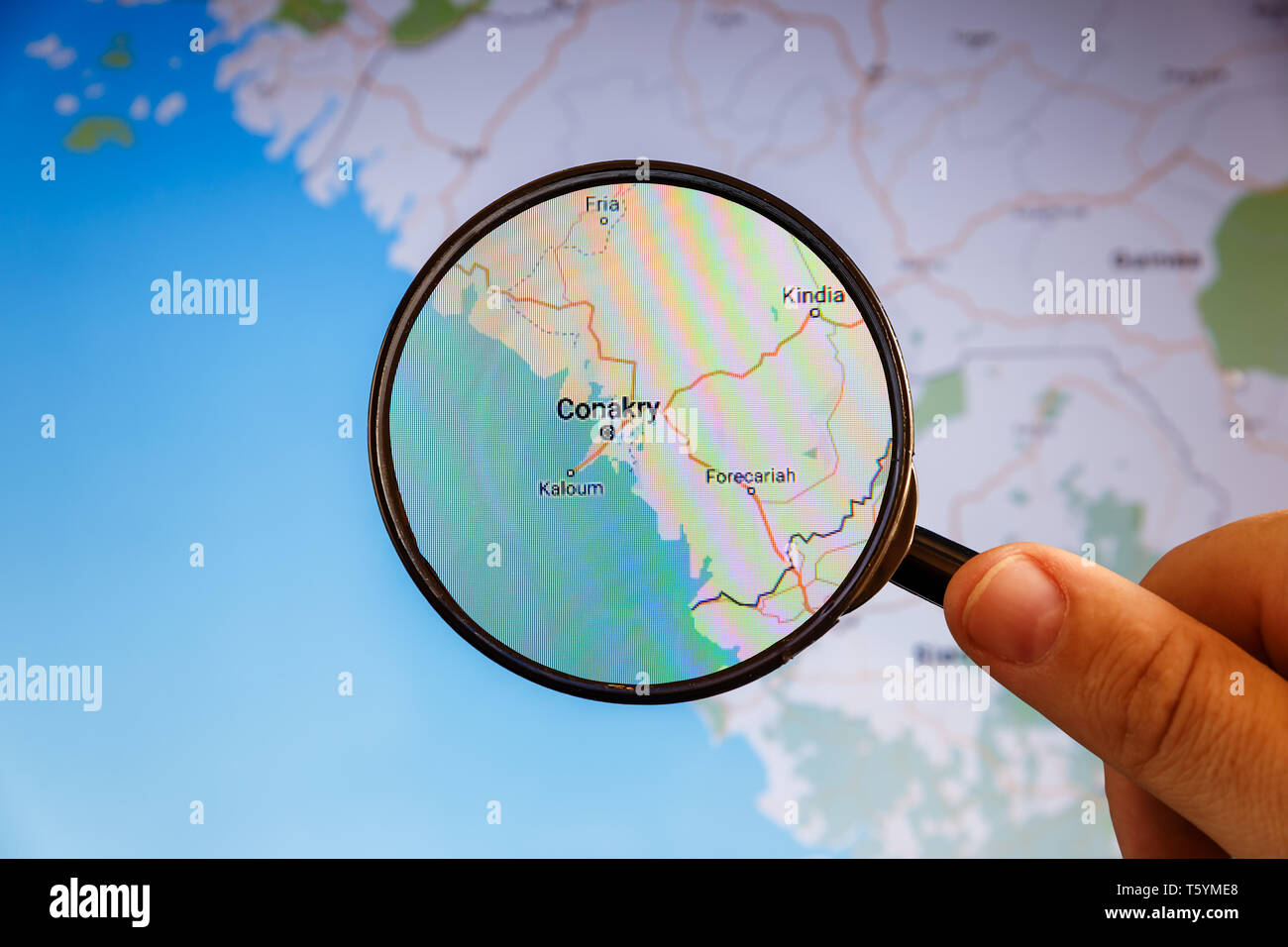 Conakry Guinea. Mappa politico. Visualizzazione della città concetto illustrativa sullo schermo attraverso la lente di ingrandimento in mano. Foto Stock