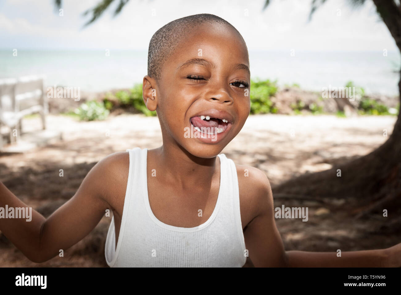 Isole Turks e Caicos Isole dei Caraibi; 14 luglio 2012; ragazzo di etnia Africican con bocca con denti mancanti e un occhio aperto cercando felice. Foto Stock