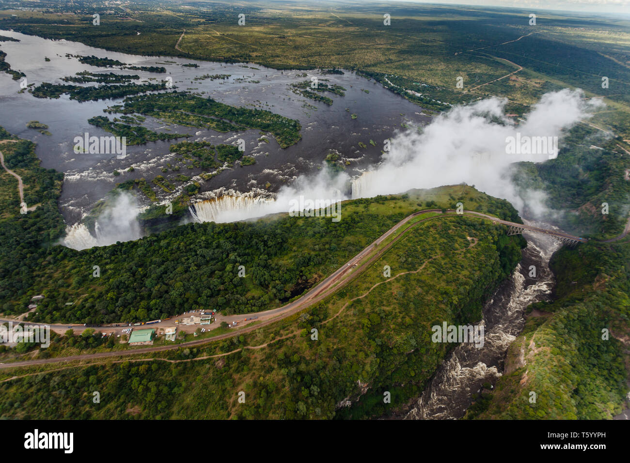 Longitudinale vista aerea dell'immenso la lunghezza del bordo di Victoria Falls e ponte in Africa con il sole che splende su di esso Foto Stock