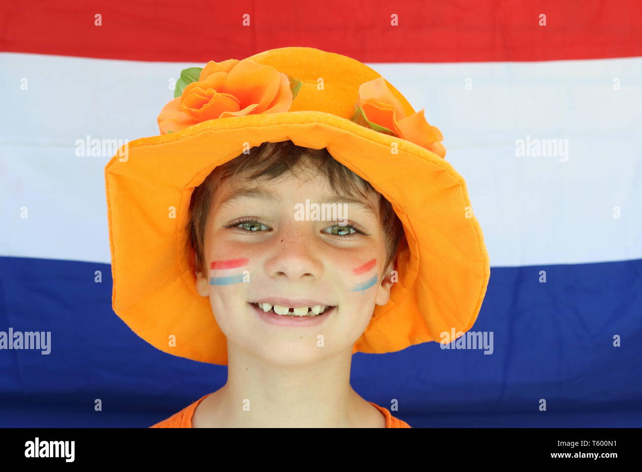 Ragazza con un grande sorriso indossando un cappello di colore arancione nella parte anteriore di una bandiera dei Paesi Bassi per celebrare il re del giorno Foto Stock