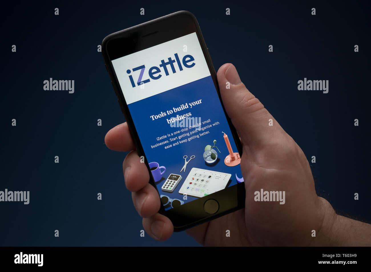 Un uomo guarda al suo iPhone che visualizza il logo iZettle (solo uso editoriale). Foto Stock