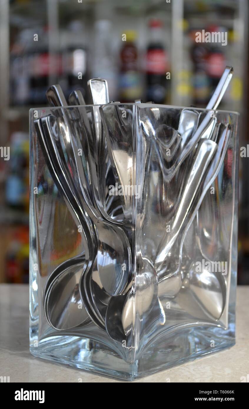 Vista ravvicinata di numerose cucchiaini collocato in un vetro solido contenitore collocato su un banco in un bar per self-service. Foto Stock