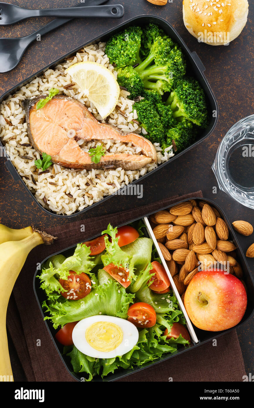 Sano e nutriente il pranzo o uno spuntino di scatole con il cibo - pesce, riso, insalata di verdure e frutta. Foto Stock