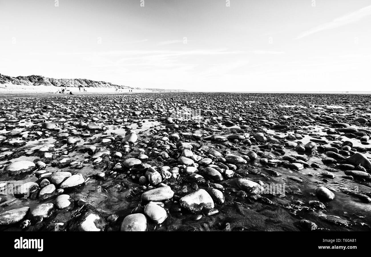 Spiaggia ghiaiosa con la bassa marea in scenic Ynyslas Beach in Galles.UK. Bianco e nero modifica Foto Stock