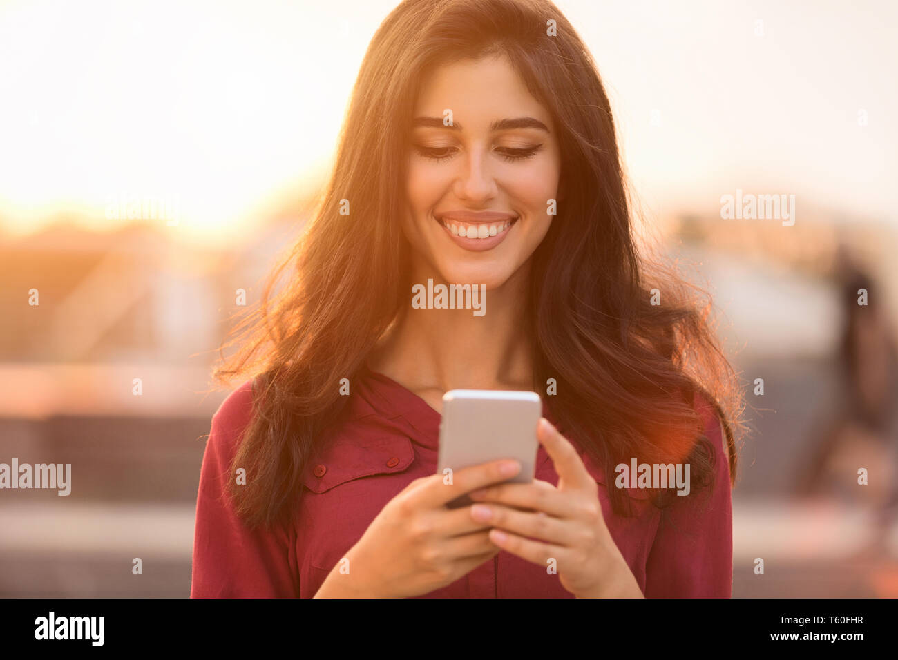 Donna felice a piedi nella città, i messaggi di testo sullo smartphone Foto Stock