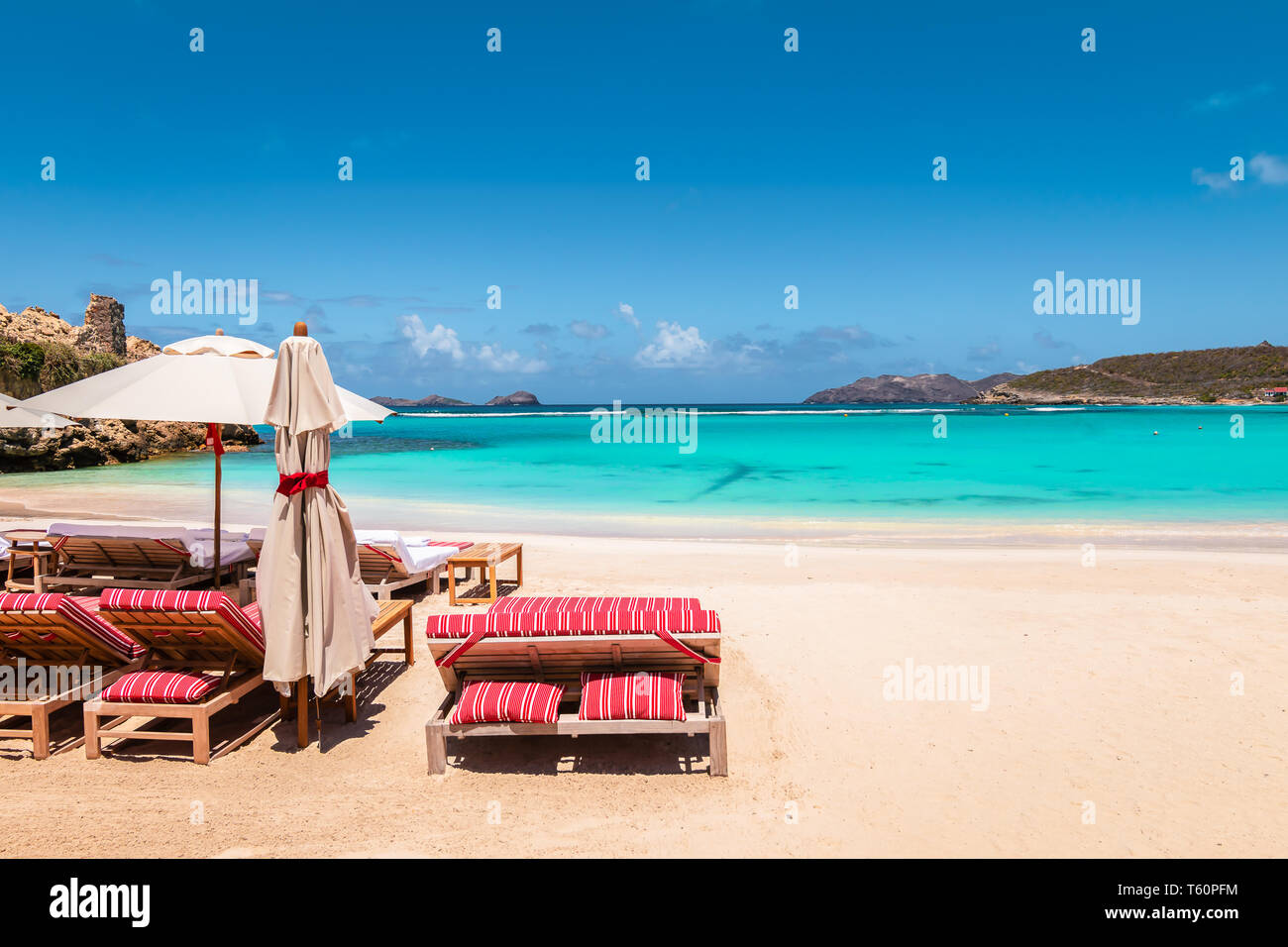 Sedie a sdraio e ombrellone in spiaggia tropicale. La vacanza estiva e il rilassamento dello sfondo. Foto Stock