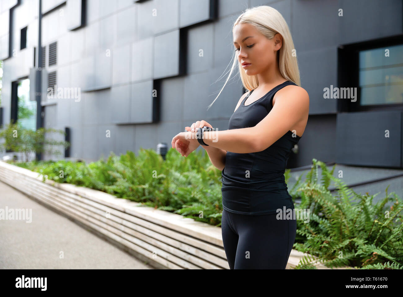 Donna controllando il suo fitness orologio smart device in ambiente urbano Foto Stock