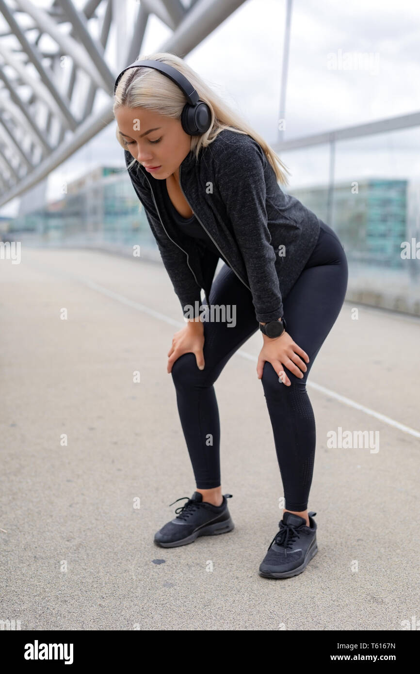 Stanco della donna in appoggio con le mani sulle ginocchia dopo l'esecuzione di allenamento Foto Stock
