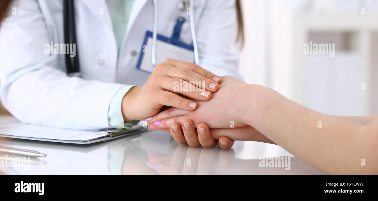 La mano di un medico donna rassicurante per paziente di sesso femminile, close-up. Etica medica e il concetto di trust Foto Stock