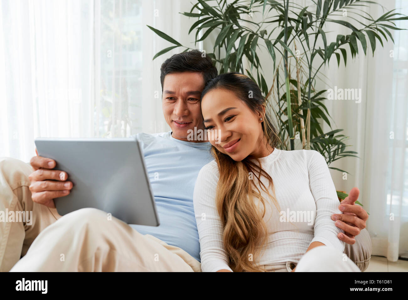 Coppia sorridente appoggiato con il computer tablet Foto Stock