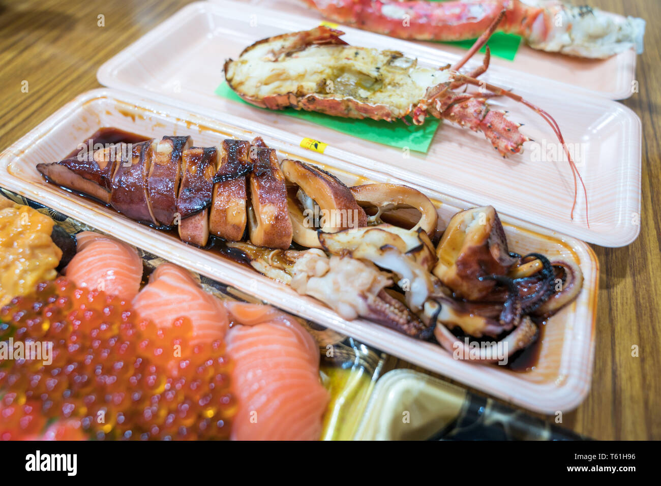 Calamari alla griglia e altri sushi; salmone, otoro, anguilla, Grigliata di gamberi, granchi sono disposti sul tavolo pronti a mangiare. Foto Stock
