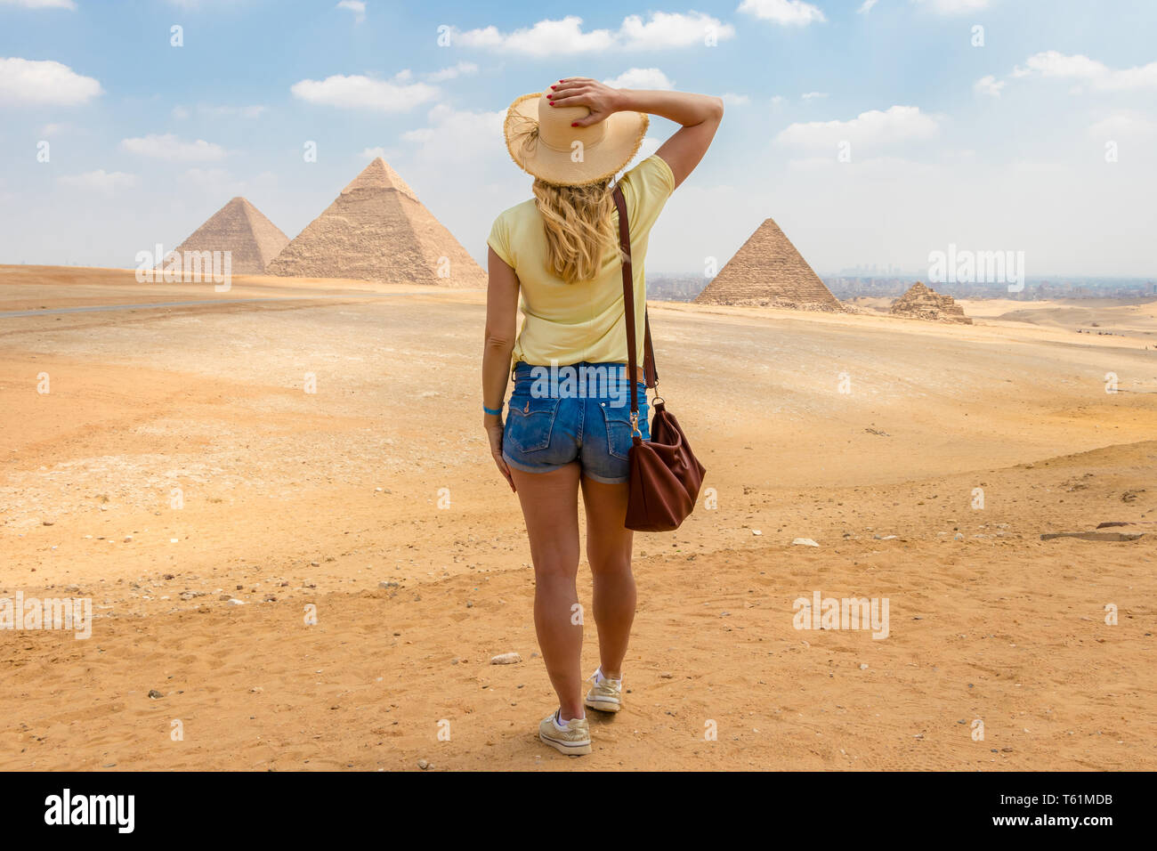 Giovane ragazza nel deserto. Vista posteriore il ritratto di una donna single che guardando le Grandi Piramidi di Giza in Egitto Foto Stock